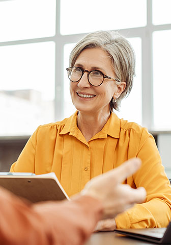 Frau in orangener Bluse beim Bewerbungsgespräch Frau in orangener Bluse beim Bewerbungsgespräch