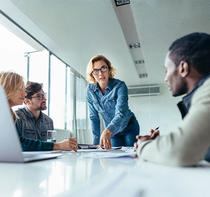 Teammeeting im Bau- und Konstruktionswesen Vier Personen sitzen an einem Konferenztisch und besprechen Bau- oder Projektpläne in einem modernen Büro.