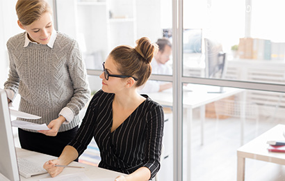 Assistenz in Bielefeld Zwei Kolleginnen besprechen Unterlagen am Arbeitsplatz im modernen Büro.