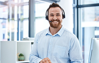Callcenter in Bielefeld Mitarbeiter mit Headset lächelt freundlich im modernen Büro.