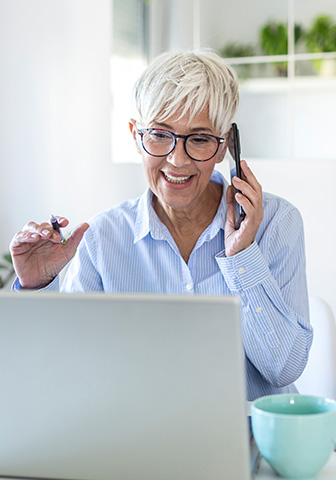Jetzt Termin buchen – Bielefeld Geschäftsfrau telefoniert und arbeitet gleichzeitig am Laptop – Terminvereinbarung.