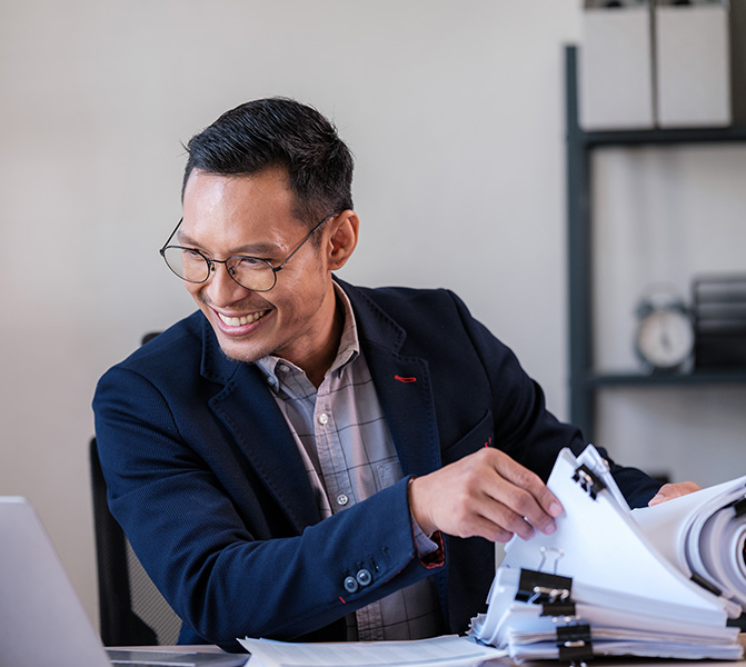 Ein Rechtsanwaltsfachangestellter sitzt am Schreibtisch und arbeitet konzentriert mit juristischen Unterlagen in einer Kanzlei in Frankfurt.
