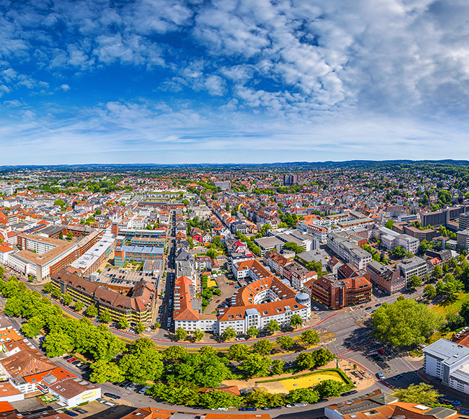 Standort Bielefeld Panoramaaufnahme der Stadt Bielefeld mit modernen Gebäuden und grünem Umfeld.