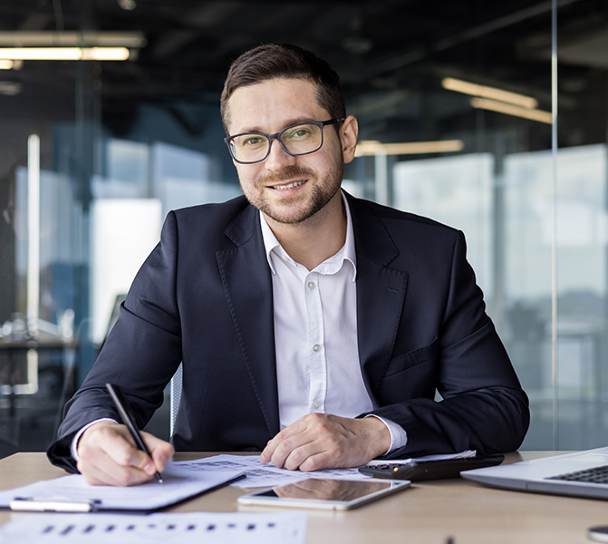 Mann im Business-Outfit arbeitet konzentriert an Dokumenten am Schreibtisch.