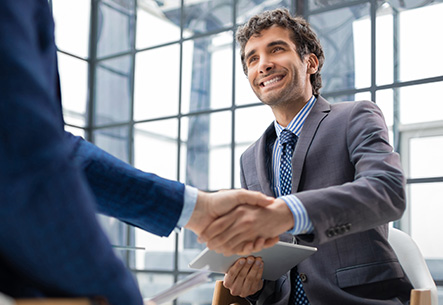 Über Unique Bielefeld Geschäftsmann im Anzug gibt einem Partner die Hand – erfolgreiches Geschäft in Bielefeld.