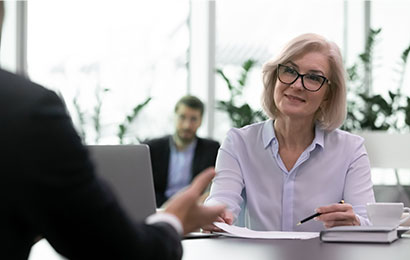 Gespräch im Finanzbereich Eine Frau mit Brille führt ein professionelles Gespräch an einem Schreibtisch in einem modernen Büro.