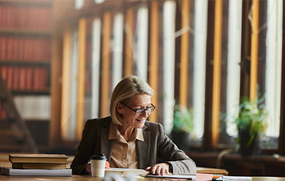 Fachbereiche Legal Juristin sitzt am Schreibtisch mit Unterlagen und arbeitet konzentriert in einer modernen Büroumgebung.