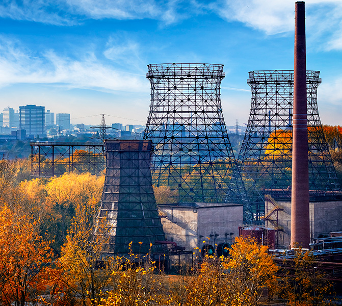 Standort Essen – Industrie und Energie Kühltürme und Industrieanlage in Essen mit herbstlicher Landschaft und Stadtansicht im Hintergrund.