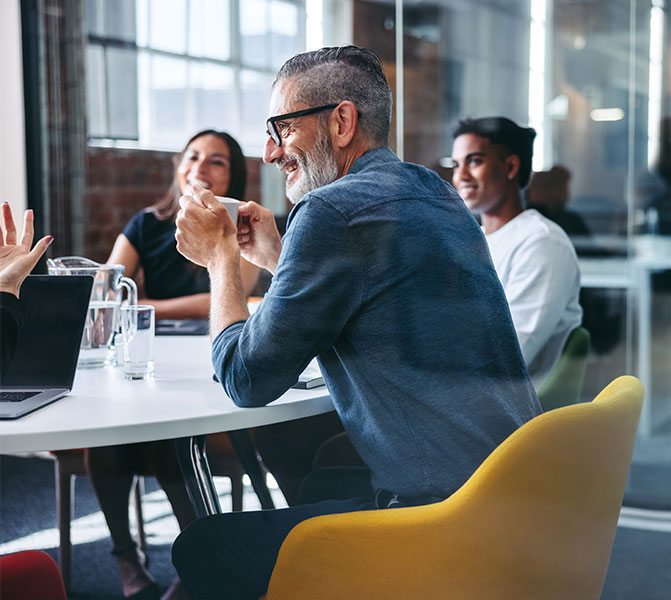 Teammeeting im modernen Büro Mehrere Kollegen sitzen zusammen am Konferenztisch und tauschen sich in entspannter Atmosphäre aus.