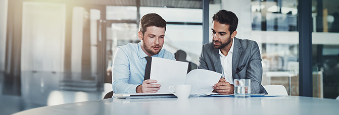 2 Personen mit einem Dokument an einem Schreibtisch