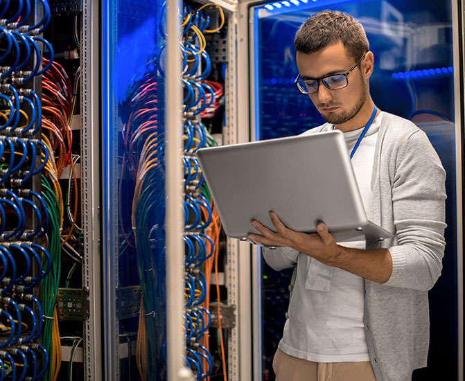 Fachbereiche IT IT-Spezialist überprüft Kabelverbindungen in einem Serverraum und arbeitet mit einem Laptop.