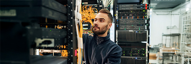 Ihre Anfrage im IT-Bereich Techniker arbeitet konzentriert im Serverraum und überprüft Kabel und Hardware.