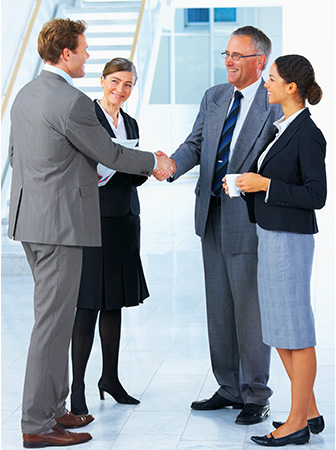 Geschäftspartner schütteln sich die Hand, während zwei weitere Kolleginnen lächeln – erfolgreicher Geschäftsabschluss.