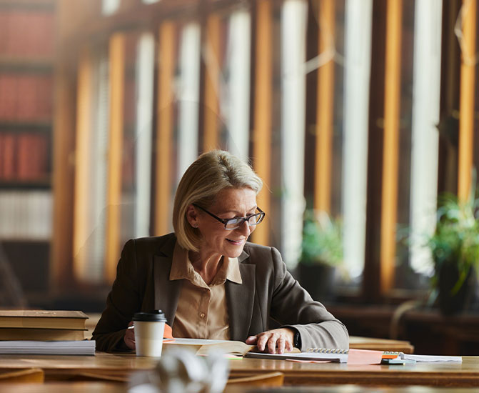 Juristin sitzt am Schreibtisch mit Unterlagen und arbeitet konzentriert in einer modernen Büroumgebung.