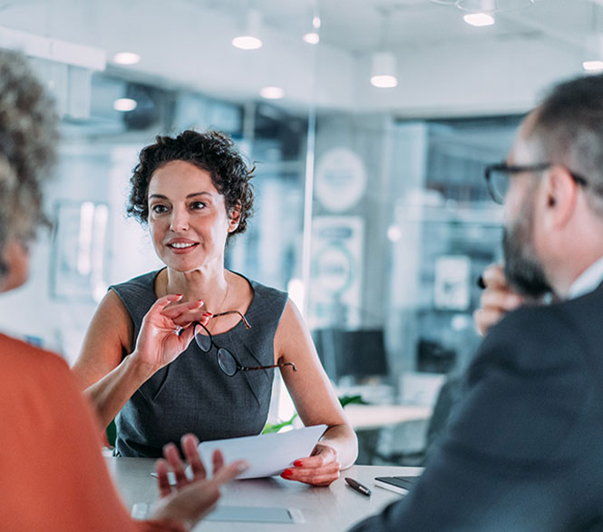 Frau im Business-Outfit im Gespräch mit Kollegen – Beratungsgespräch im modernen Büro.