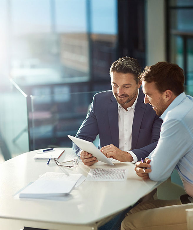 Active Sourcing über Social Media Zwei Geschäftsmänner sehen gemeinsam auf ein Tablet und besprechen Recruiting-Strategien.