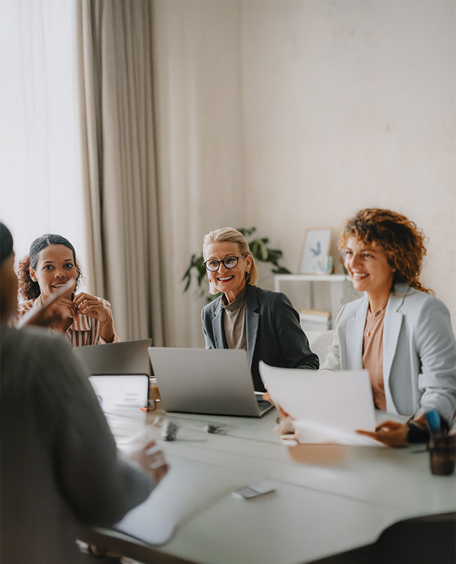 Active Sourcing und weitere Leistungen Drei Business-Frauen sitzen gemeinsam im Meeting und arbeiten an Laptops.