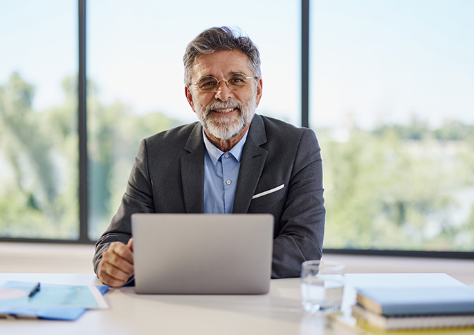 Ihre Talentsuche Geschäftsmann mit Laptop lächelt in die Kamera – professionelle Unterstützung bei der Talentsuche.