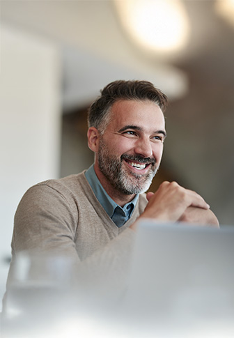 Warum Active Sourcing? Geschäftsmann mit grauem Pullover lächelt während eines Gesprächs – moderne Recruiting-Methoden.