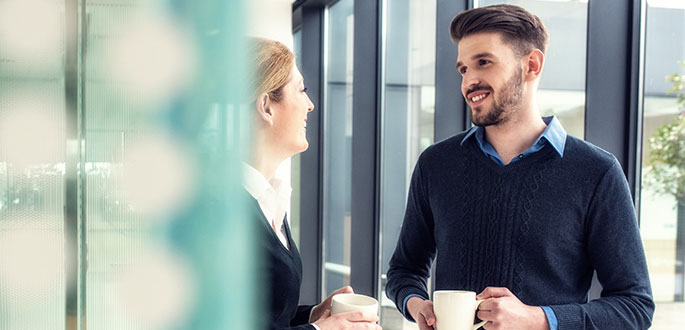 Gespr&auml;chsituation mit Kaffetasse auf dem Flur eines Unternehmens