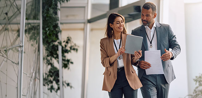 Zwei Gesch&auml;ftsleute besprechen Unterlagen und digitale Inhalte und stehen f&uuml;r professionelle Zusammenarbeit, Austausch und gemeinsame L&ouml;sungen.
