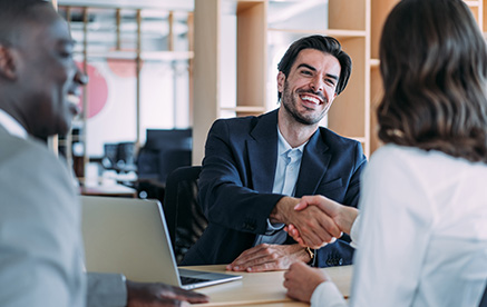 Exklusiv und priorisiert Geschäftsmann lächelt und schüttelt einer Partnerin die Hand – erfolgreiche Zusammenarbeit.