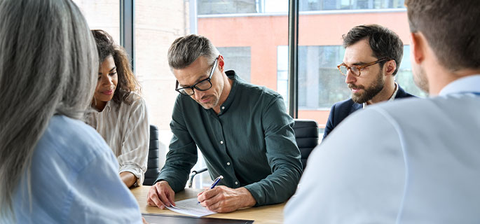 Team von Gesch&auml;ftsleuten arbeitet gemeinsam an einem Tisch &ndash; Zusammenarbeit und Vertragsfindung.
