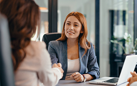 Standardisiert und verlässlich Geschäftsfrau im Meeting gibt einer Kollegin die Hand – Vertrauen und Partnerschaft.