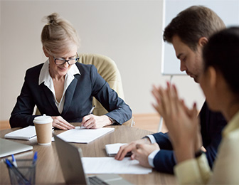 Vertragsmodelle – Ihre Vorteile Geschäftsfrau im Business-Outfit schreibt im Meeting Notizen auf Papier.